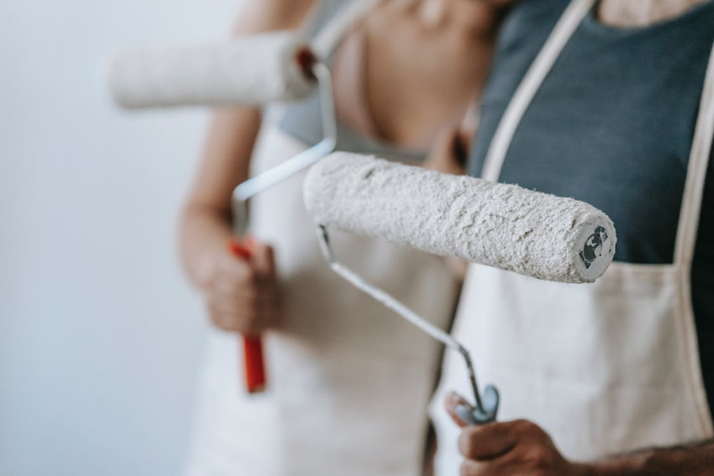 A photo showing two people holding paint rollers