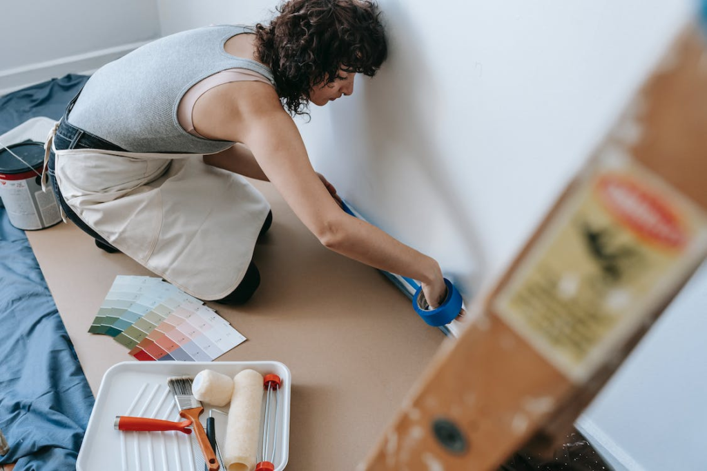  A photo showing a woman applying tape to a wall