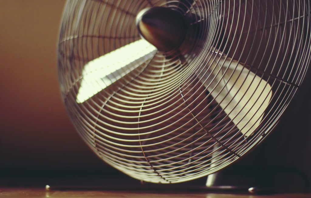 A photo showing a steel fan resting on a wood surface