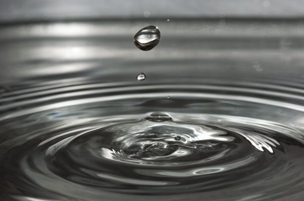 A photo showing a water droplet floating above a body of water.