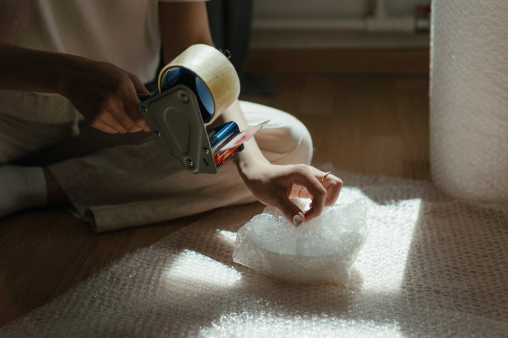 A photo showing a person wrapping items in bubble wrap.