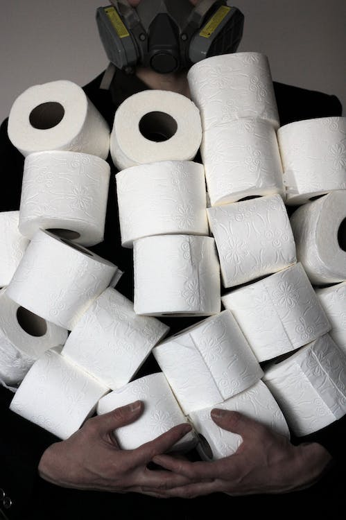 A photo showing a person carrying a stack of tissue rolls.